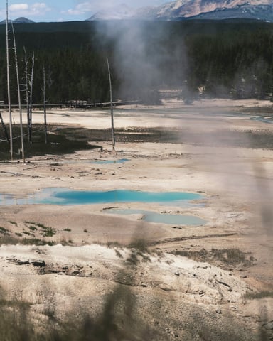Natural hot springs steaming with mountains behind